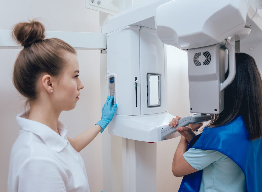 Young woman patient standing in x ray machine.