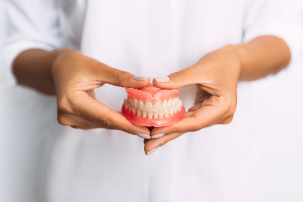 The dentist is holding dentures in his hands. Dental prosthesis