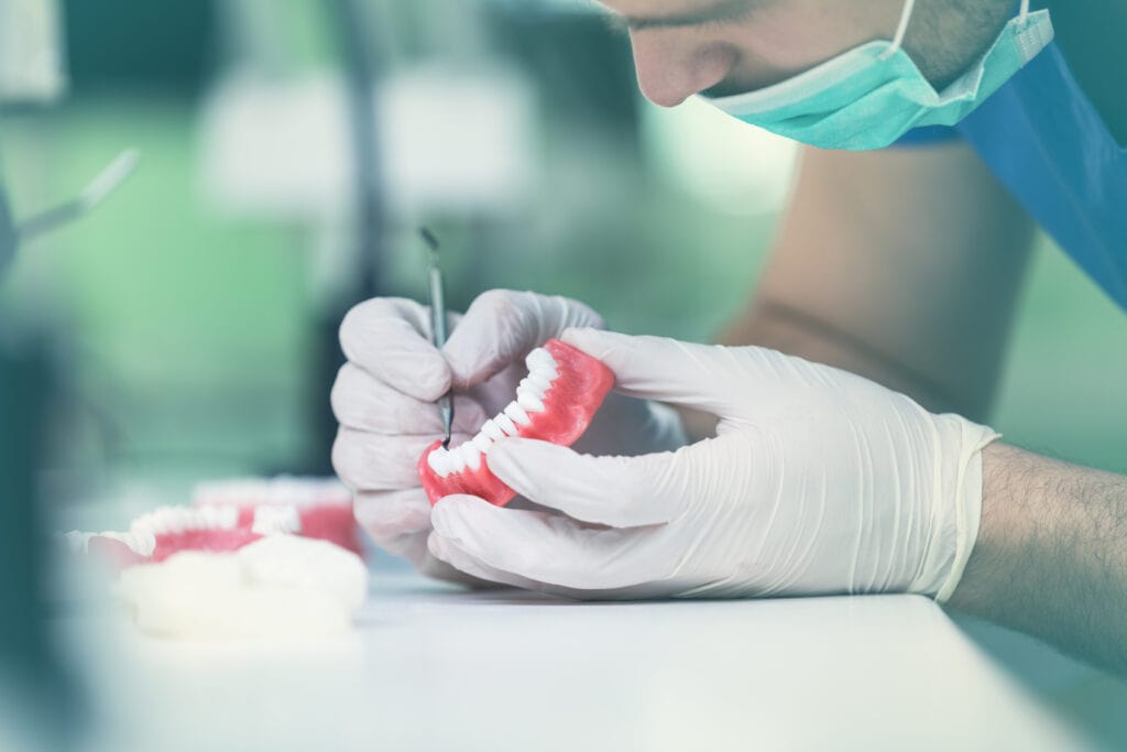 Dental prosthesis, dentures, prosthetics work. Dental students while working on the denture, false teeth, a study and a table with dental tools.